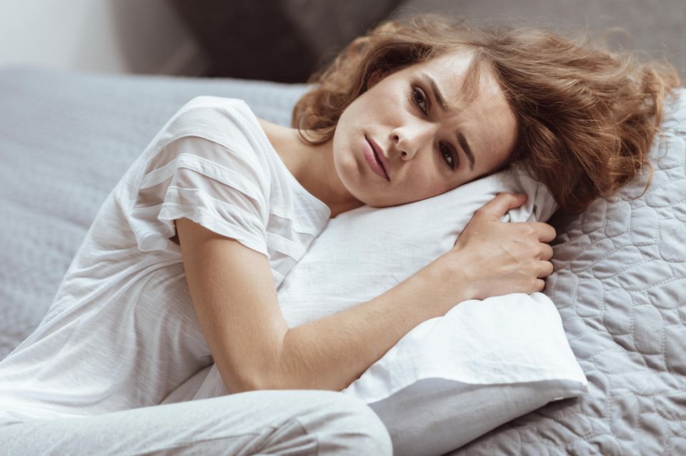 Selbstmitgefühl: Frau liegt traurig auf dem Sofa