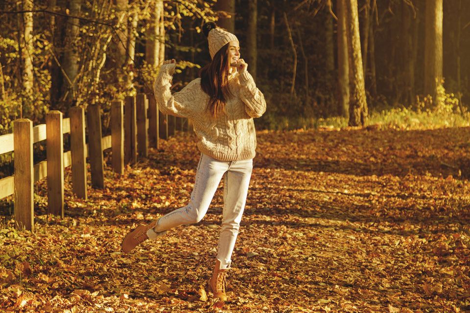 Eine Frau tanzt in der Herbst-Landschaft
