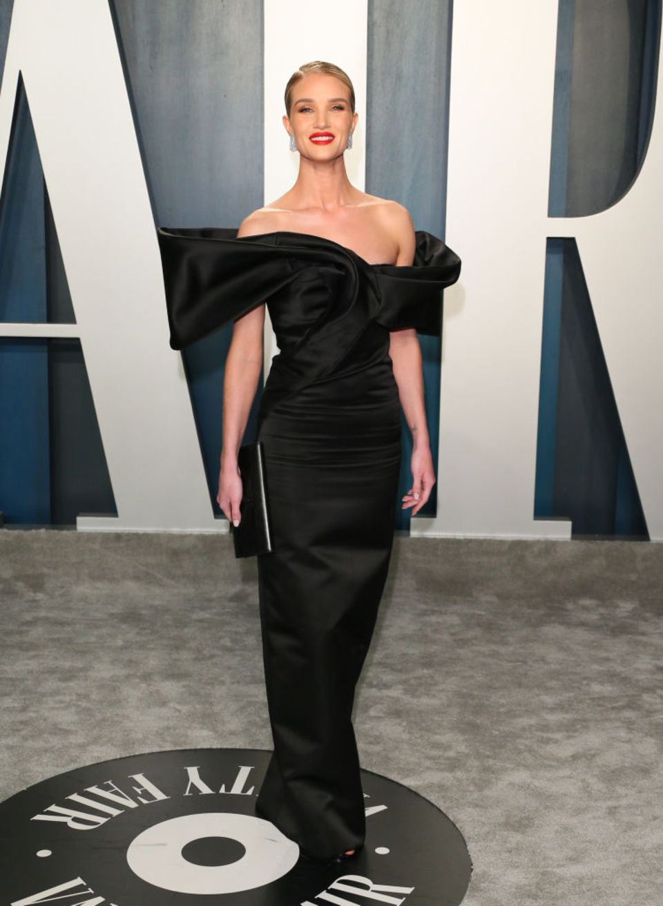 Model Rosie Huntington-Whiteley präsentiert sich bei der Vanity Fair Oscar Party 2020 in einem schwarzen Kleid und zeigt dabei ihr sexy Schlüsselbein. Die Schauspielerin kombiniert das Kleid mit einer passenden schmalen Clutch in der gleichen Farbe und zwischen ihren roten Lippen blitzt ein perfektes Zahnpastalächeln hervor. Was für ein Auftritt! 