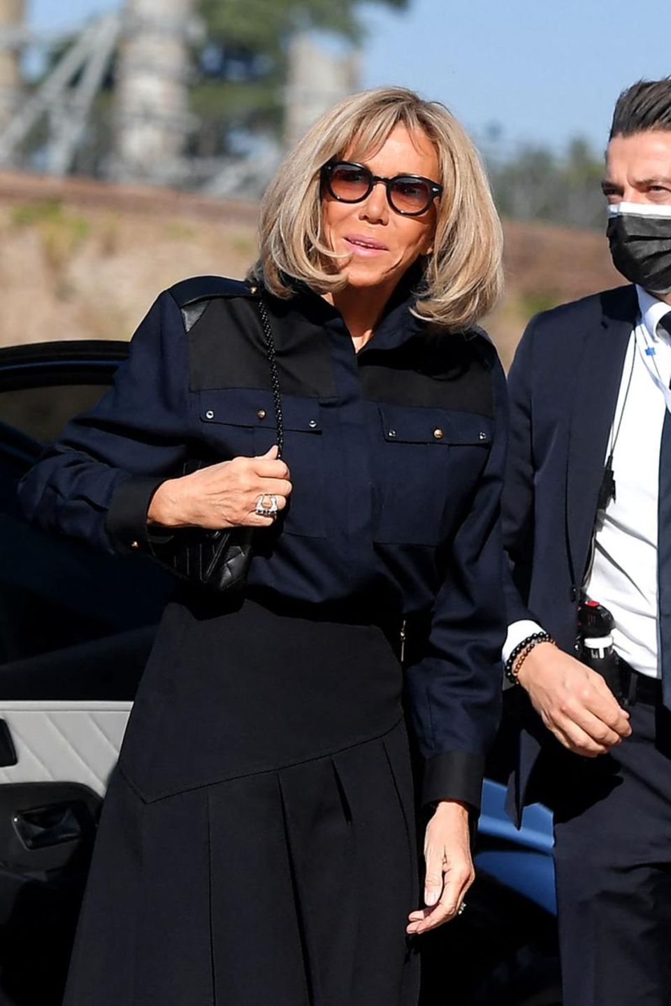 Brigitte Macron kommt am Rande des G20-Gipfels 2021 zu einem privaten Besuch zum Kolosseum in Rom. Die Französin trägt eine dunkelblaue Oversized-Bluse mit dezenten Nieten auf den Brusttaschen. Macron kombiniert das Hingucker-Piece mit einem schwarzen hochgeschnittenen Faltenrock und einem gleichfarbigen Wallet-On-Chain. Den sportlich schicken Look rundet die Frau des französischen Prätendenten mit einer schwarzen Sonnenbrille und silbernem Schmuck ab. 
