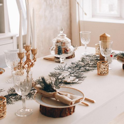 Weihnachtstrends 2021: Gedeckte Tafel mit Tannen, Kerzen, Gläsern, Tellern und Besteck