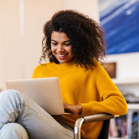 Fröhliche Frau am Laptop: Diese 8 Gewohnheiten pflegen erfolgreiche Menschen täglich