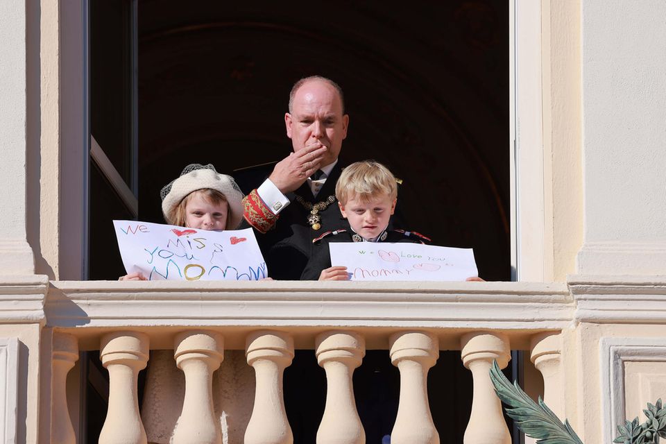 Die Zwillinge senden ihrer Mutter eine rührende Botschaft vom Balkon des Fürstenpalastes in Monte-Carlo. Prinzessin Gabriella hat auf ihr Plakat "Wir vermissen dich, Mami" geschrieben. Ihr Bruder Jacques hält ein Schild mit der Aufschrift "Wir lieben dich, Mami" in die Luft. 