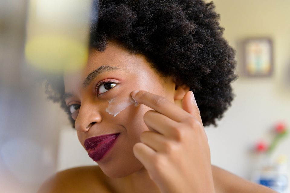 Wie schädliche Umwelteinflüsse unser Hautbild prägen: Frau vor dem Spiegel