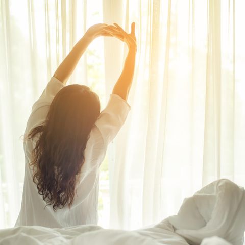 Frau streckt sich im Bett: Wer um diese Uhrzeit aufsteht, ist am erfolgreichsten