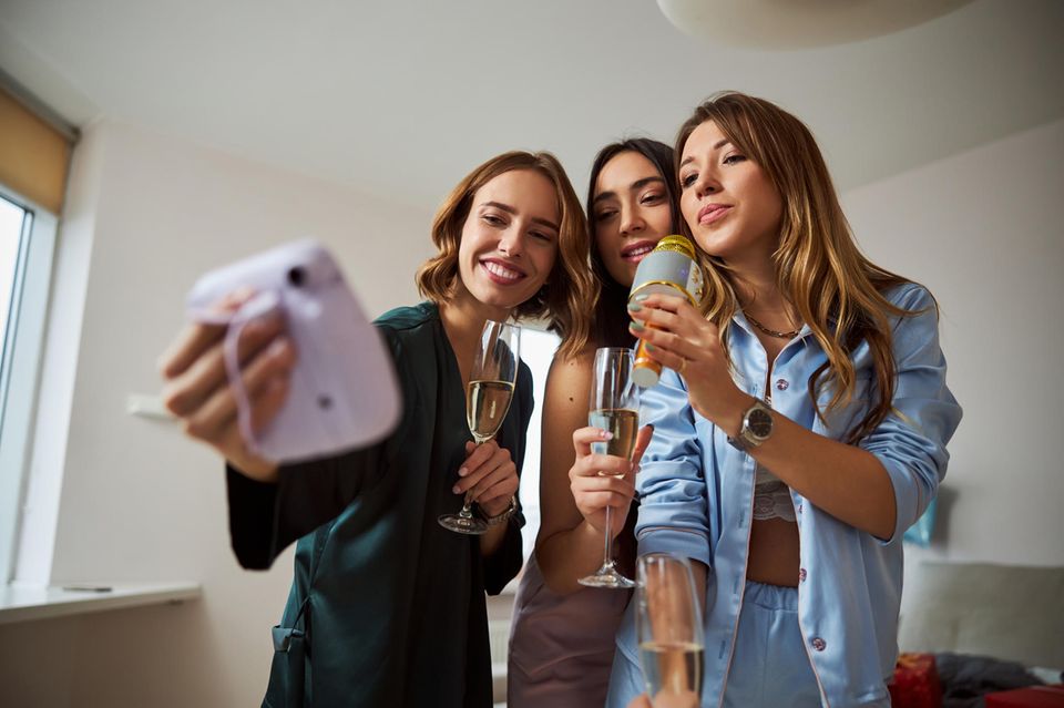 Drei Frauen posieren vor einer Instant-Kamera