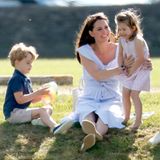 Kate liebt das Mama-Dasein: In leichtem Sommerkleid und mit überschlagenen Beinen tollt sie 2018 mit ihren Kindern herum. Seit April sind es drei, nachdem Prinz Louis auf die Welt gekommen ist.