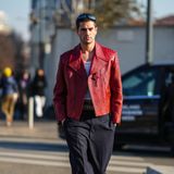 Male Model Marc Forne zeigt auf dem Weg zur Prada-Show seinen lässigen Streetstyle mit roter Lederjacken und Anzughose mit Nadelstreifen.