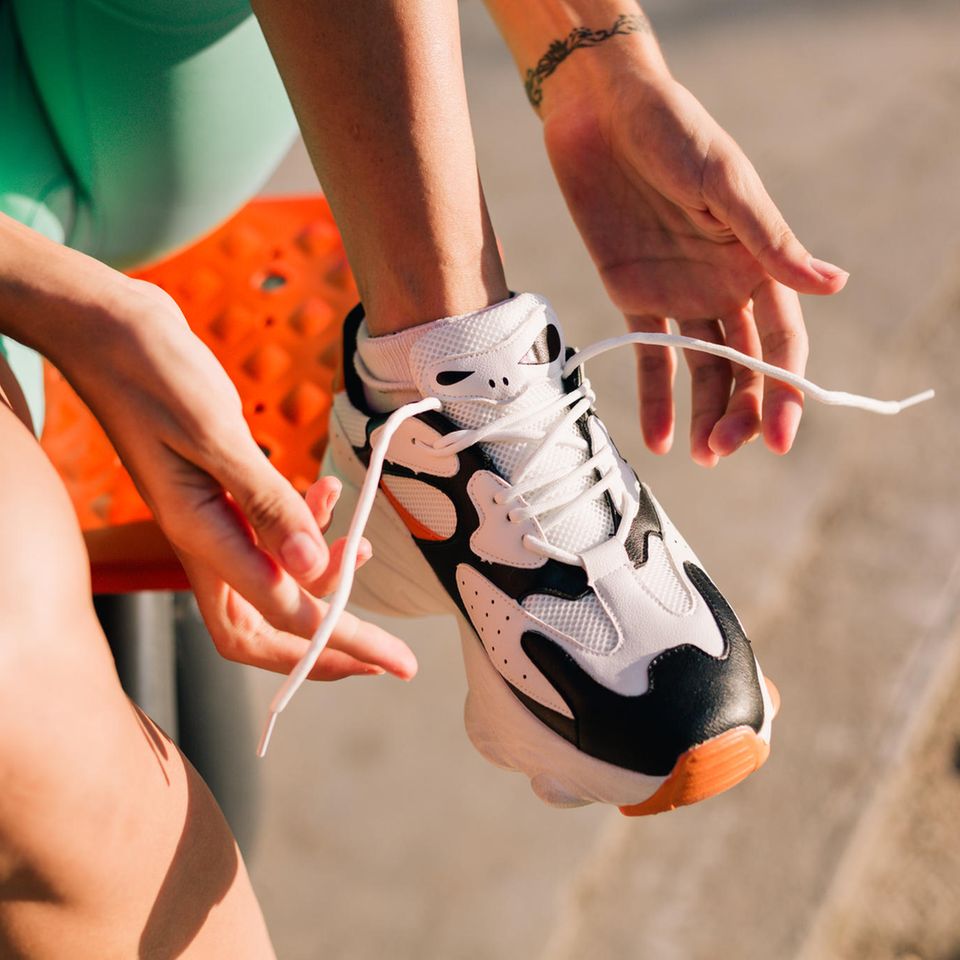 vegane Sneaker in der Sonne werden von einer Frau zugeschnürt