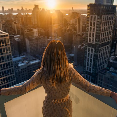 Horoskop: Frau auf dem Balkon vor Skyline