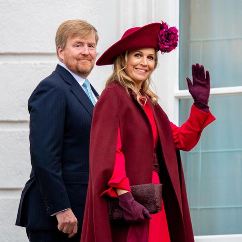 Königin Máxima winkt den Fotografen zu, Willem-Alexander lächelt hinter ihr