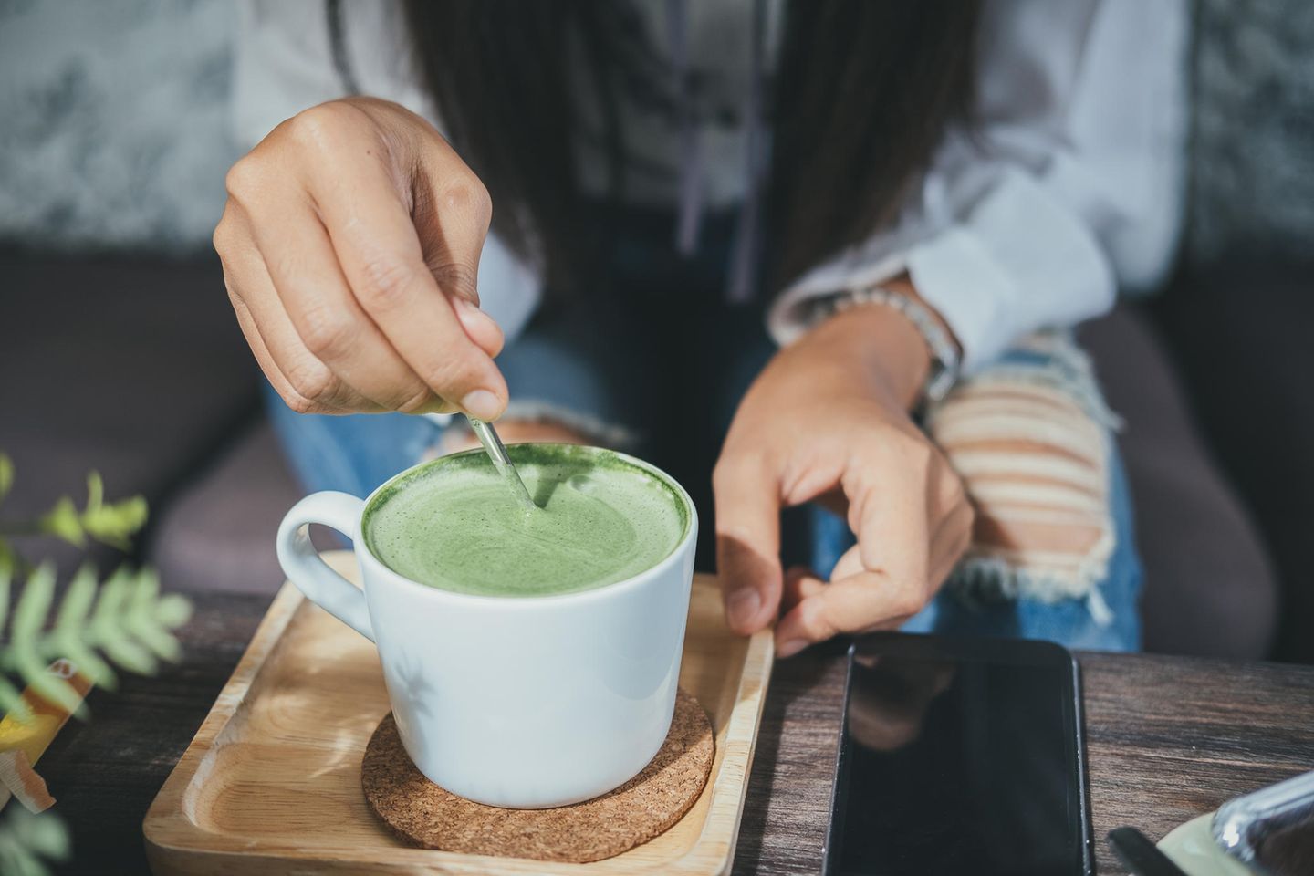 Frau rührt in Matcha-Tee: Diese 5 gesunden Lebensmittel sind im Übermaß ungesund