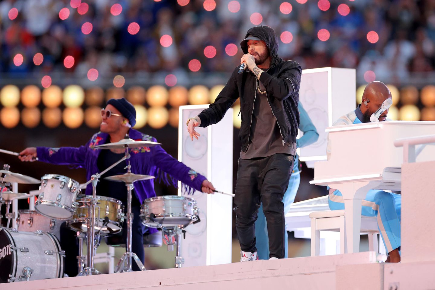 2022  Rapper Eminem legt in der Halbzeitpause des Superbowl 2022 in Los Angeles einen fulminanten Auftritt hin. Sein Look? Ganz im Hip-Hop-Style locker lässig und super cool. Schwarze Hose, graues Shirt, schwarzer Hoodie und Basecap, dazu weiße Sneaker und eine große Goldkette – so kennt man den Musiker.  