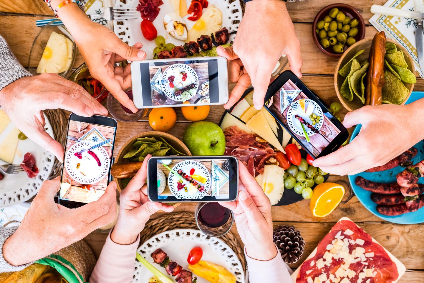 Food-Trends 2022: Gedeckter Tisch mit 4 Händen, die mit ihrem Smartphone Fotos machen