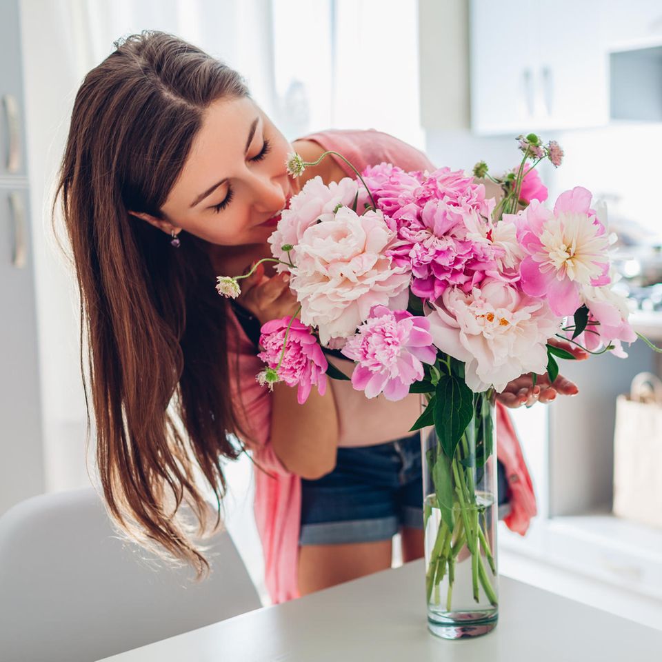 Eine dunkelhaarige Frau riecht an einem Blumenstrauß