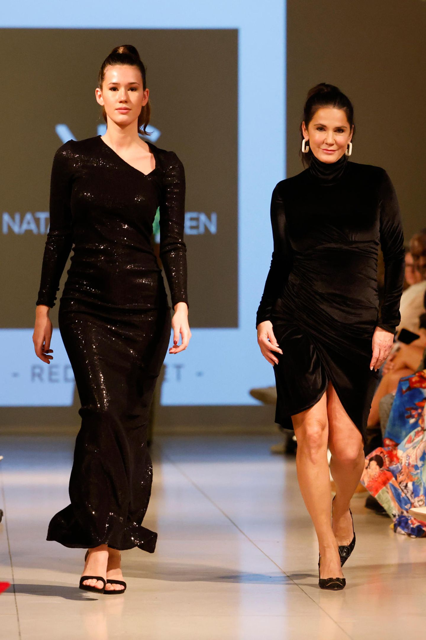 Gemeinsam mit ihrer Tochter Isabella läuft Mariella Ahrens über den Catwalk von Natascha Gruen. Beide in sehr eleganten, schwarzen Kleidern.