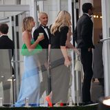 Auch Romeo Beckham setzt auf einen schwarzen, klassischen Anzug in Schwarz mit Fliege. Seine Freundin Mia Regan trägt ein hellblaues Fit-and-Flair-Kleid. Dazu kombiniert das Model eine grüne Clutch.
