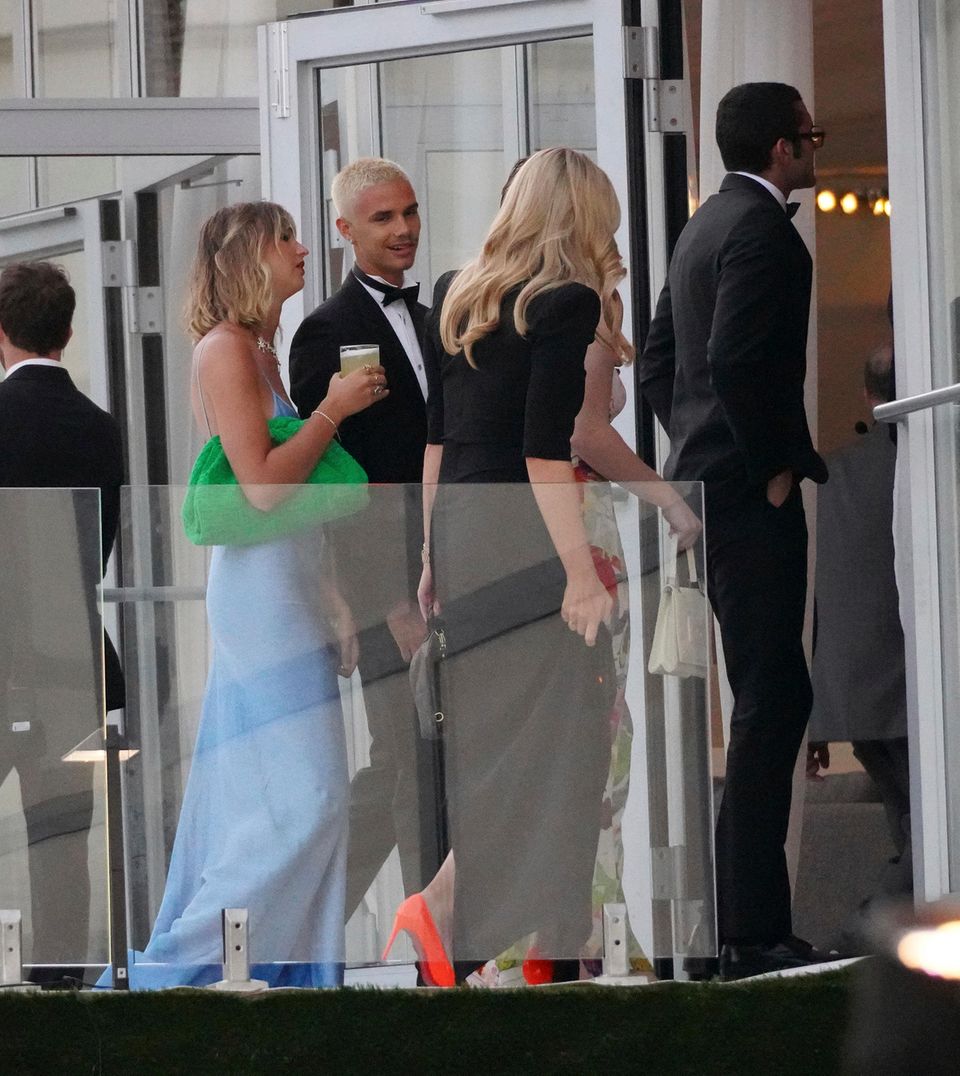 Victoria Beckham: Romeo Beckham und Mia Regan. Auch Romeo Beckham setzt auf einen schwarzen, klassischen Anzug in Schwarz mit Fliege. Seine Freundin Mia Regan trägt ein hellblaues Fit-and-Flair-Kleid. Dazu kombiniert das Model eine grüne Clutch.