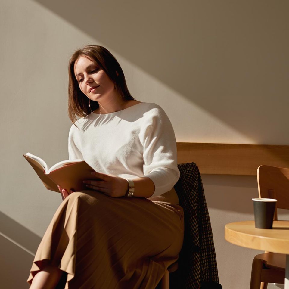 Frau liest Buch im Café