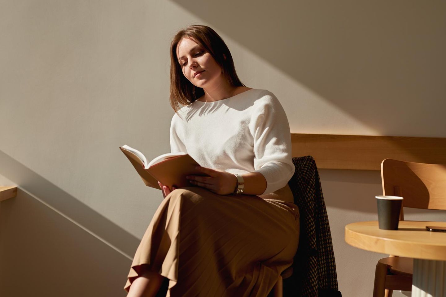 Frau liest Buch im Café