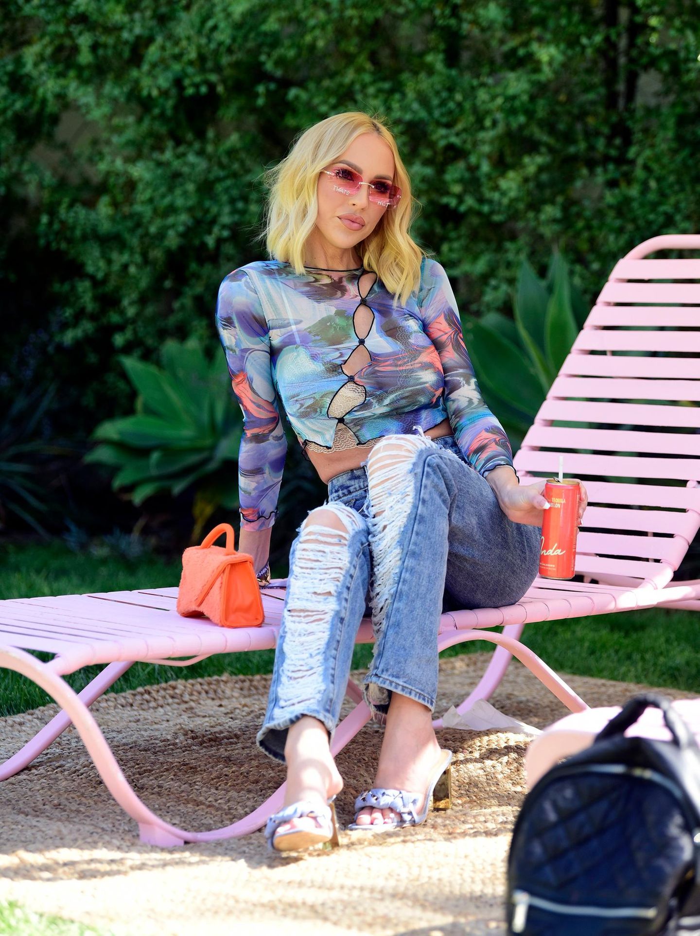 Auch Netflix-Star Christine Quinn wärmt sich mit einem Drink für das Wochenende auf. Dabei trägt sie eine lässige Jeans mit Destroyed-Look und ein halbtransparentes Shirt mit wildem Muster.
