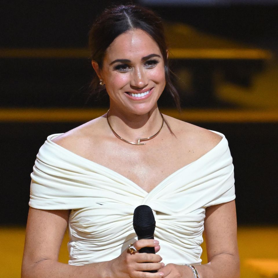 Bei der Eröffnungszeremonie der Invictus Games bekommt Herzogin Meghan nicht nur aufgrund ihrer bewegenden Rede zu Ehren von Ehemann und Initiator Prinz Harry große Aufmerksamkeit – auch ihr besonderes Outfit zieht alle Blicke auf die 40-Jährige. Sie trägt ein weißes, schulterfreies Oberteil von Khaite mit einer schwarzen Hose. Das Besondere: Ihr Look erinnert an eine der letzten Aufnahmen ihrer verstorbenen Schwiegermutter Lady Diana...