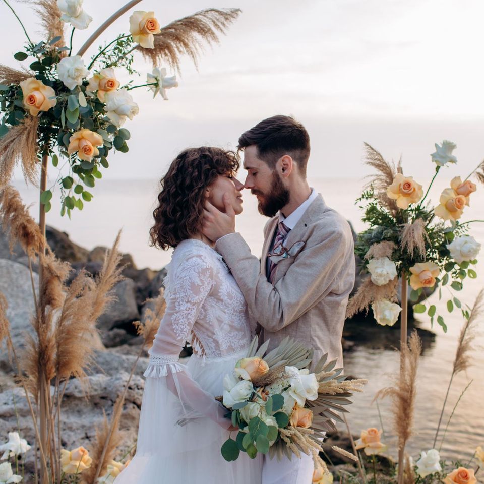 Mann und Frau küssen sich auf ihrer Boho-Hochzeit am Meer