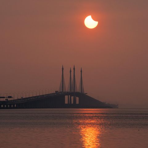 Partielle Sonnenfinsternis am 30.4.2022: Eine partielle Sonnenfinsternis über einem Hafen
