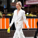 Klassisch mit Farbtupfern. Julianne Hough trägt einen weißen Anzug-Zweiteiler mit Wickel-Detail. Dazu trägt sie gelbe Jimmy Choo Schuhe und die passende Handtasche. Außerdem möchte Julianne damit ein Zeichen der Solidarität setzen, da der Anzug von Elena Burenina, einer ukrainischen Designerin ist.