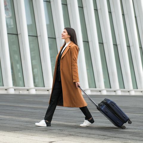 brünette Frau mit eine Schwarzen Handgepäck-Koffer