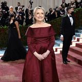 Politikerin Hilary Clinton strahlt in einem schulterfreien Satin-Look in Bordeauxrot.