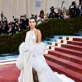 Schwanengleich zeigt sich Hailey Bieber im seidigen Feder-Dress von Yves Saint Laurent. Nur die schwarzen Nylons wollen dazu nicht so recht passen.