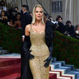 Einen ähnlichen Look wie ihre Schwester Kim zeigt Khloe Kardashian. Sie kombiniert den goldenen Glamour-Look von Moschino allerdings mit einem schwarzen Satin-Cape und passenden Handschuhen.
