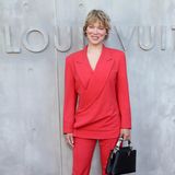 Léa Seydoux wählt einen Anzug in einem frischen roten Farbton, ihre Kurzhaarfrisur mit 80er-Jahre-Flair und das strahlende Lächeln sind die perfekten Begleiter.