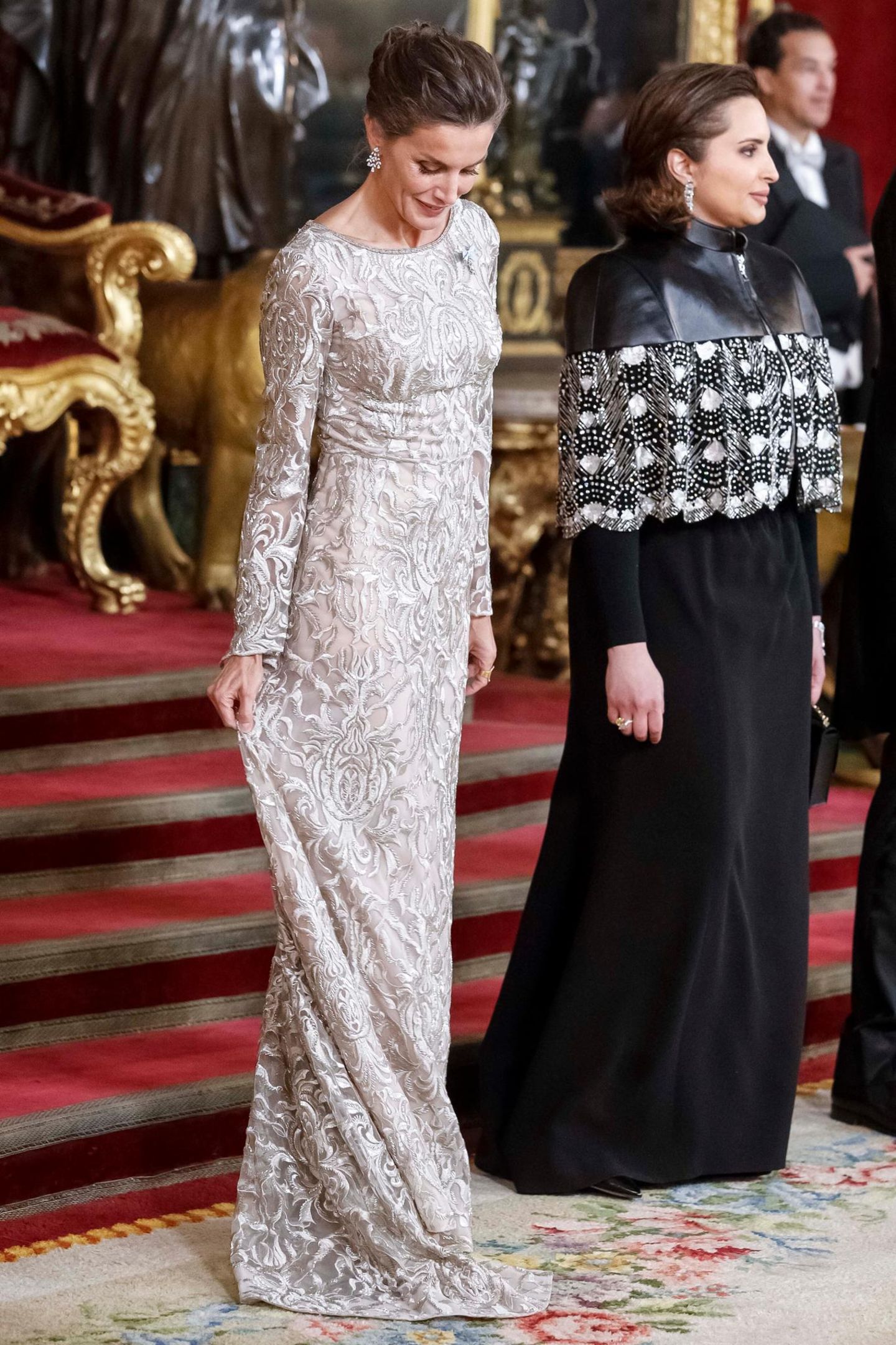 In Madrid wird die katarische Königsfamilie von König Felipe und Königin Letizia von Spanien zum Gala-Dinner empfangen. Für den Besuch beeindruckt uns Letizia wieder einmal mit ihrem Look: Sie trägt ein langes silberfarbenes Kleid, das mit glänzender Spitze besetzt ist und durch transparente Trompeten-Ärmel verzaubert. Mit ihrer Frisur betont sie zusätzlich ihre funkelnden Ohrringe.