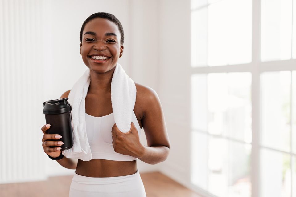 Frau trinkt Kaffee nach dem Sport: Das sind die 4 besten Lebensmittel gegen Muskelkater