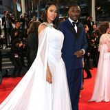 Idris Elba ist mit seiner Frau in Cannes zu Gast. Während er mit einem dunkelblauen Anzug auf die klassische Variante setzt, begeistert Eve in einem weißen Tüllkleid im Toga-Stil.