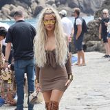Khloe Kardashian ist in diesem knappen braunen Kleid und Wildleder-Overkneeboots ebenfalls auf dem Weg zur Party auf der Yacht von Dolce & Gabbana.