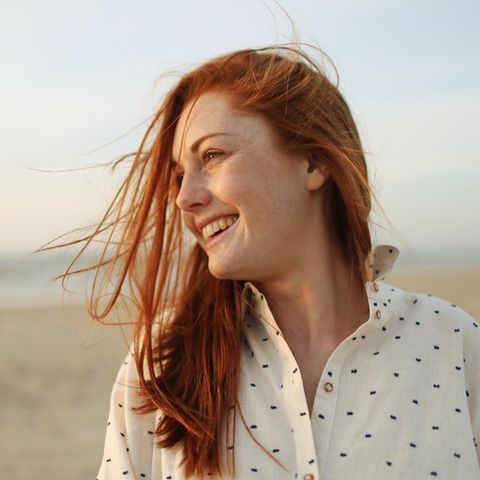 Innere Zufriedenheit: Glückliche Frau lächelnd am Strand