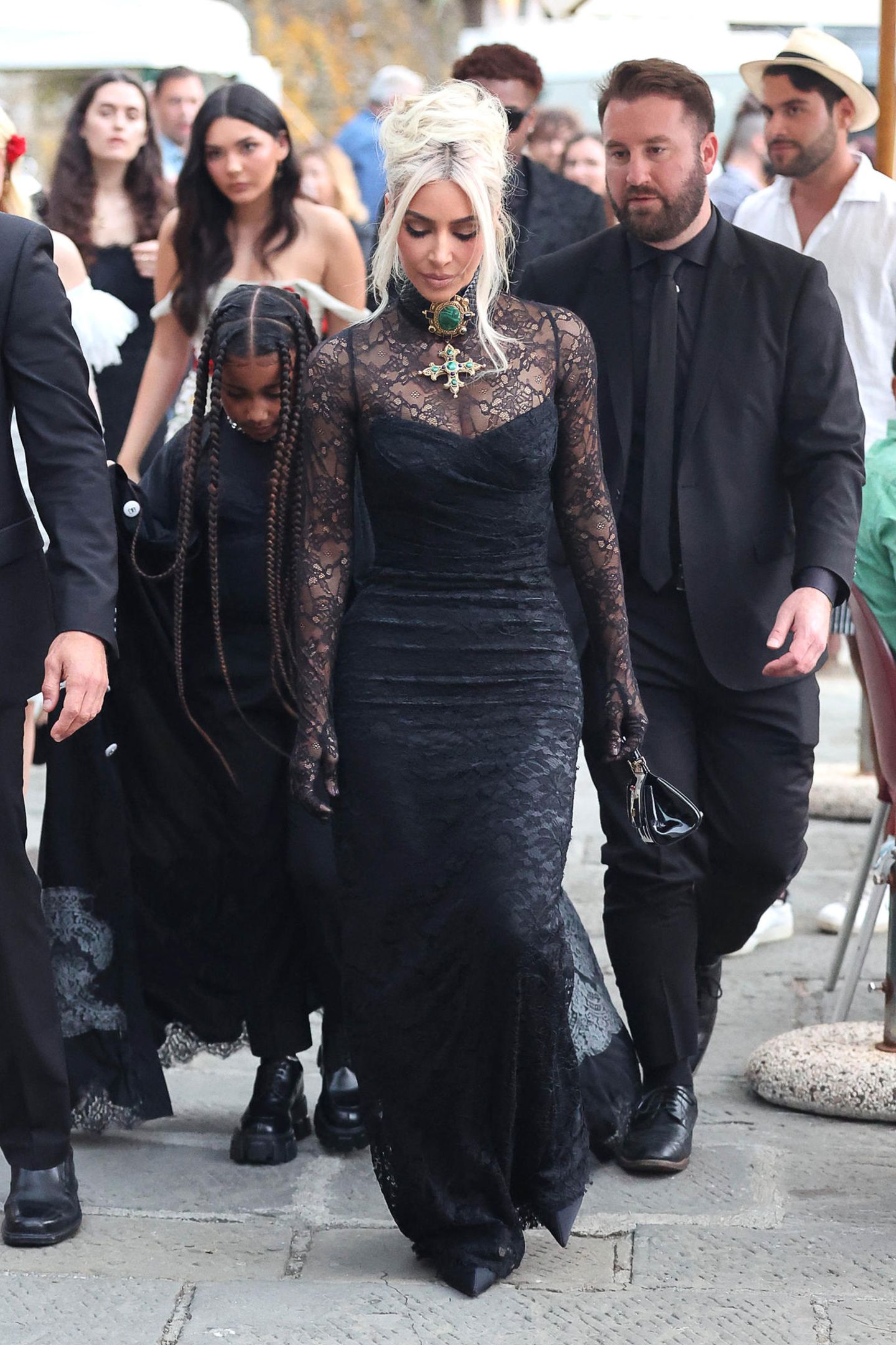 Kim Kardashian zeigt sich für die tatsächliche Hochzeit in einem hochgeschlossenen schwarzen Spitzenkleid von Dolce & Gabbana mit integrierten Handschuhen. Dazu setzt die 40-Jährige auf eine massive Kreuzkette. 