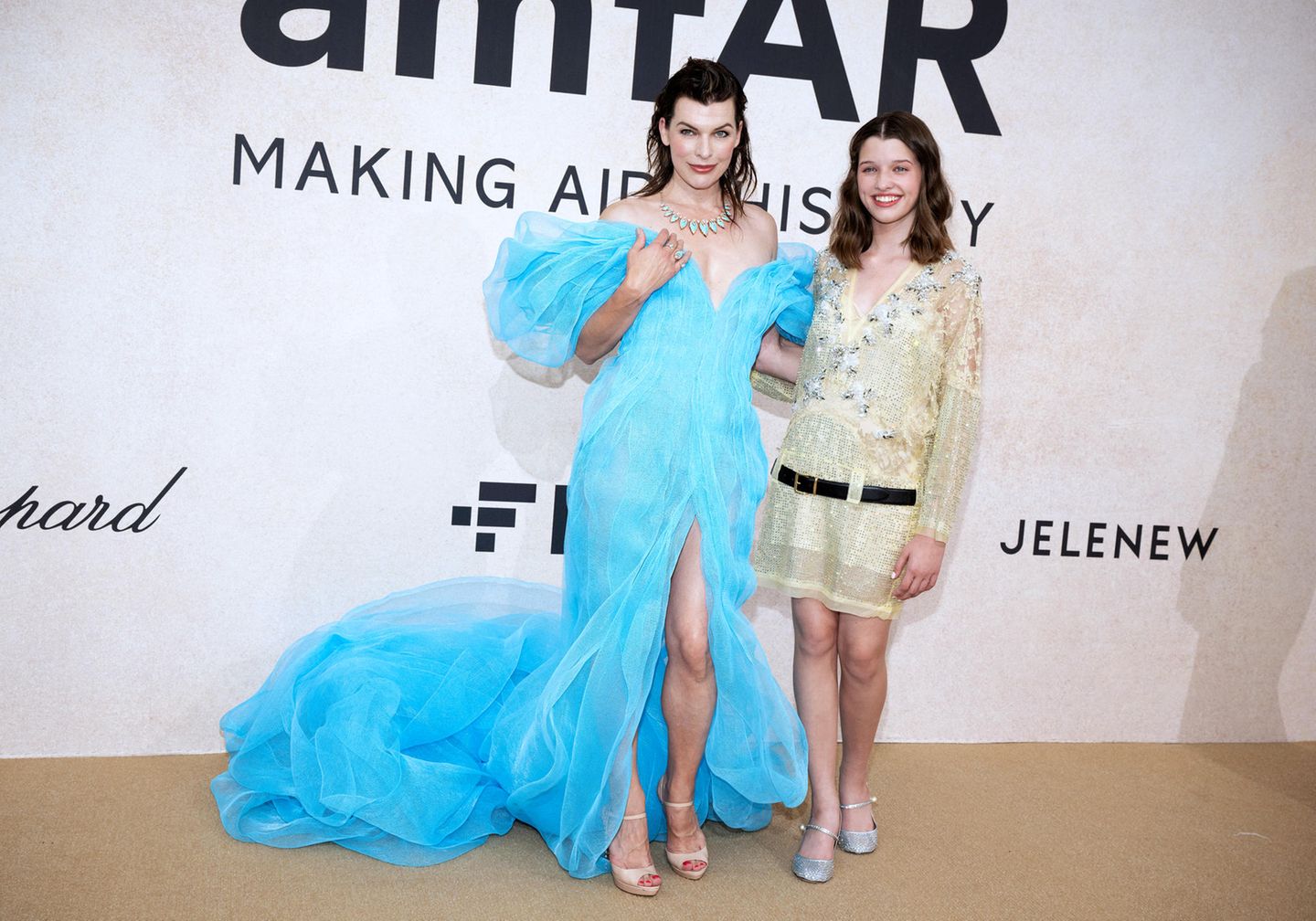 Mutter-Tochter-Style mit Statement: Milla Jovovich trägt einen hellblauen Tülltraum des ukrainischen Modellabels Lever und passenden Schmuckstücken von Messika, Tochter Ever Anderson in pastellfarbiger Anlehnung an die ukrainische Flagge dazu einen süßen Glitzerlook in Hellgelb.