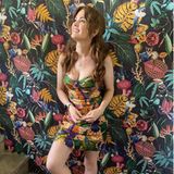 Welch ein Zufall! Isla Fisher scheint vor dem Hintergrund der farbenfrohen Tapete fast zu verschwinden. Der Grund ist das ebenso bunte Muster ihres Kleids von Farm Rio, das dem der Wanddeko zum Verwechseln ähnlich sieht – eine stylische optische Täuschung.
