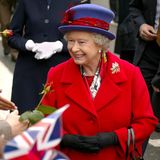Die Queen lächelt die vor ihr stehenden Menschen an.