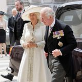 Herzogin Camilla zeigt sich an der Seite von Prinz Charles in einem elfenbeinfarbenen Mantelkleid aus festem Seidenstoff, das an den Säumen kunstvoll verziert ist.