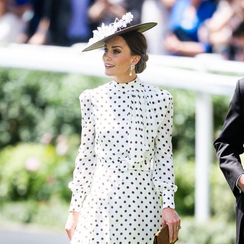 Bei ihrem Besuch in Ascot zeigt sich Herzogin Catherine in einem gepunkteten Midikleid mit Schluppe und Taillengürtel von Alexandra Rich. Dazu trägt sie einen passenden Hut in schwarz-weiß und braune Accessoires. Der Look steht Kate nicht nur hervorragend, er ist auch eine schöne Hommage an ihre verstorbene Schwiegermutter Prinzessin Diana.