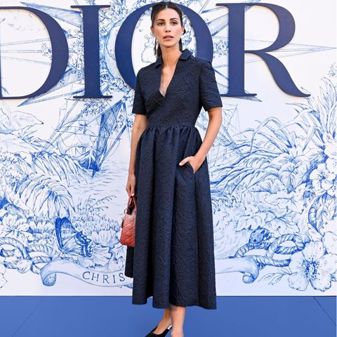 Alessandra de Osma besucht die Cruise Show von Dior in einem dunkelblauen Mididress im Hemdstil. Dazu kombiniert sie Kitten Heels und eine Handtasche – natürlich von dem französischen Label.