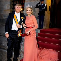Königin Máxima und König Willem-Alexander der Niederlande veranstalteten ein Galadinner in Amsterdam. Mit diesem Look macht sich Máxima zum absoluten Hingucker – sie trägt ein orangenes Kleid mit langer Schleppe, Blüten-Details und einem roten Satin-Band um die Taille – dazu trägt sie die passende Clutch. Ihre Halskette und Krone machen ihren Look umso spektakulärer.