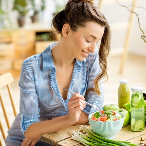 Frau isst Salat am Tisch