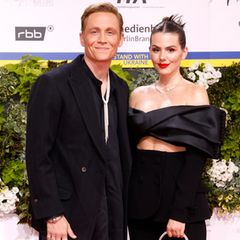 Ein Glamour-Paar darf auf dem roten Teppich des Deutschen Filmpreises natürlich nicht fehlen: Matthias Schweighöfer und Ruby O. Fee. Letztere hat sich wieder einmal für rote Lippen entschieden, die zu ihren dunkelbraunen Haaren unheimlich elegant aussehen. Viel braucht es mit so einem Power-Make-up nicht. Ein schwarzer Zweiteiler und eine rote Tasche als Eyecatcher perfektionieren ihren Look. Freund Matthias bleibt beim All-Black-Look, einzig ein Kettenelement oberhalb seiner Brust bietet farblichen Kontrast. 