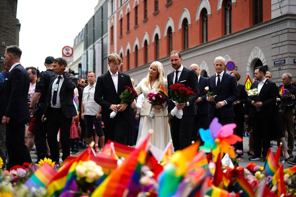 25. Juni 2022  Oslo steht nach dem Terroranschlag auf einen Nachtclub der queeren Szene mit 2 Toten und vielen Verletzten unter Schock. Trotz höchster Terrorwarnstufe kommen Hunderte trauernde Menschen zusammen, die am Samstag eigentlich eine fröhliche Pride Parade feiern wollten. Auch Prinzessin Mette-Marit und Prinz Haakon zeigen zusammen mit Sohn Sverre Magnus ihre aufrichtige Anteilnahme.